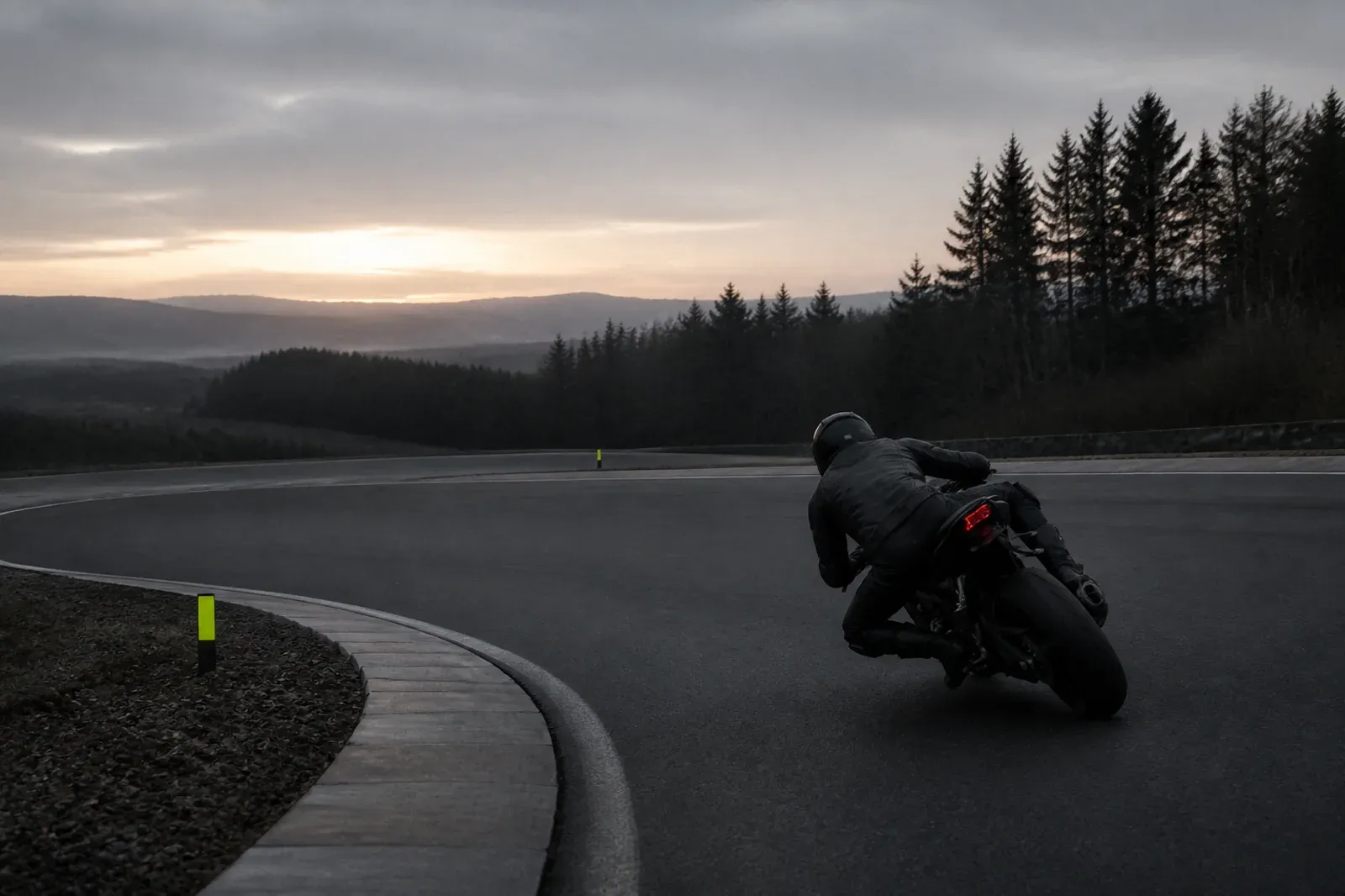 Motorcyclist leaning through a corner on a closed-road lean-angle research route at dawn